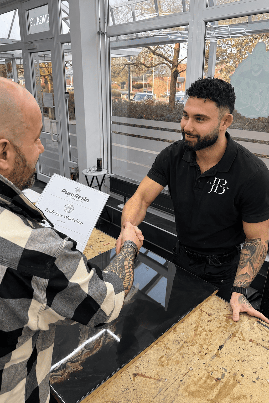 Teilnehmer erhält nach erfolgreichem Abschluss eines Pure Resin Flooring Workshops sein Zertifikat für professionelle Epoxidharz-Bodenbeschichtungen.
