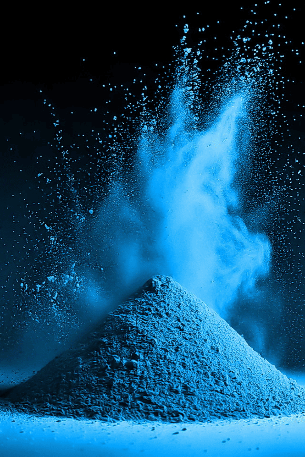 Leuchtend blaues Metallic-Pigmentpulver wirbelt über einem kleinen Haufen auf schwarzem Hintergrund auf.