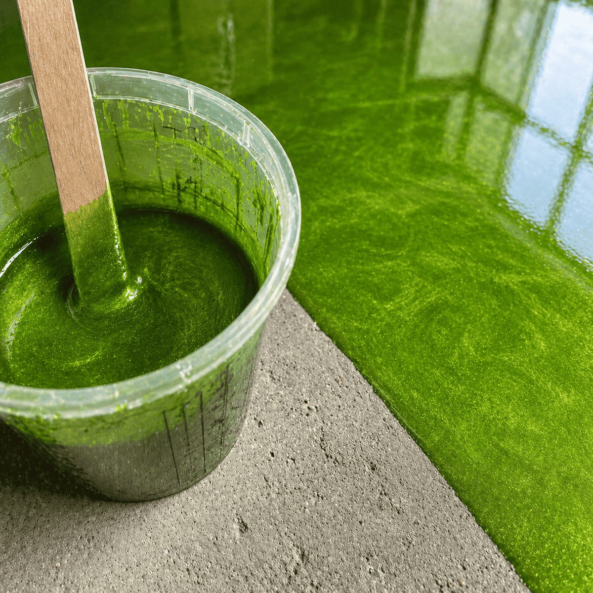 Apple Green UV Metallic-Epoxidharz im Mischbecher neben einer fertigen Musterplatte mit leuchtender Apfelgrün-Optik, luxuriöser Marmorstruktur, brillantem Perleffekt und hochglänzender Tiefenwirkung.