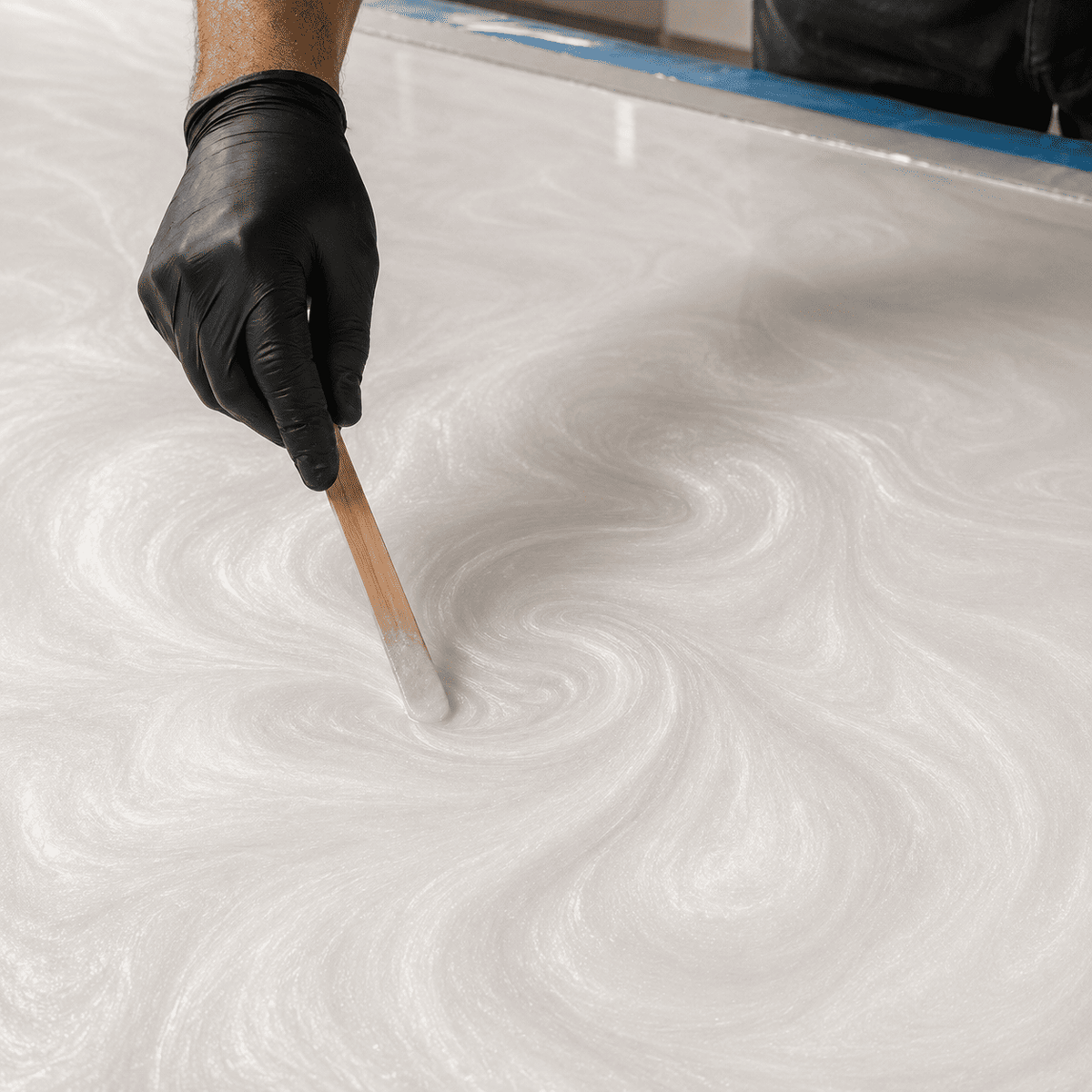Weißes Metallic-Epoxidharz wird mit einem Holzstab zur eleganten Marmorstruktur gestaltet