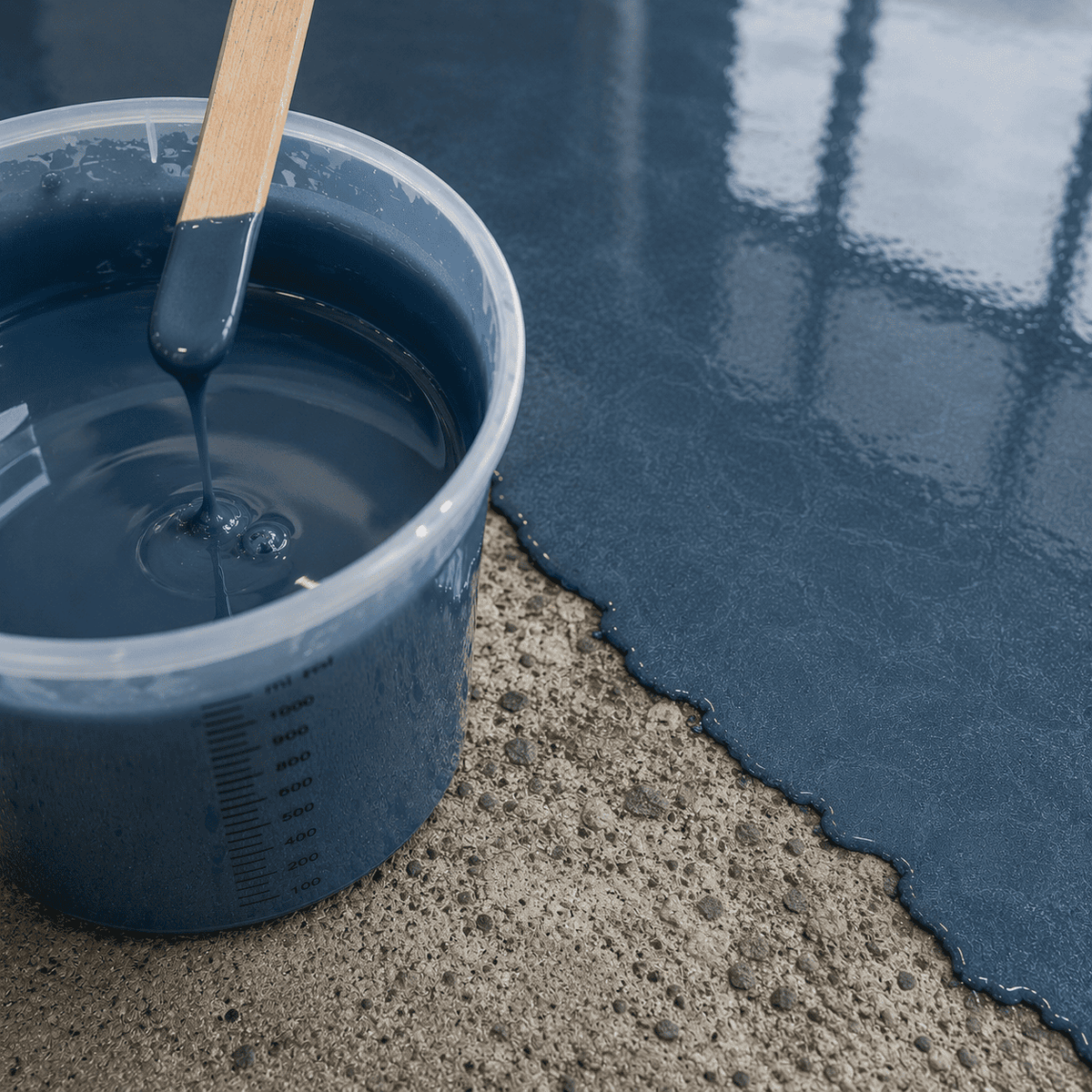Cambridge-blaues Metallic-Epoxidharz im Mischbecher neben einer frisch beschichteten Betonfläche mit feinem Perleffekt, elegantem Metallglanz und dezenter Marmorstruktur.
