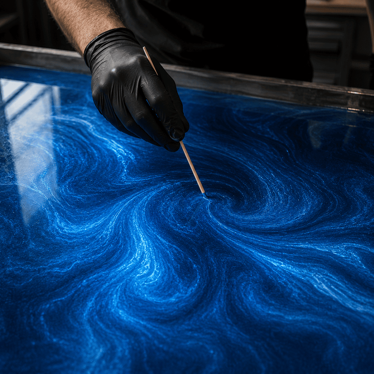 Kobaltblaues Metallic-Epoxidharz wird mit einem Holzstab zu einer dynamischen Marmorstruktur mit intensiver Tiefenwirkung gestaltet.