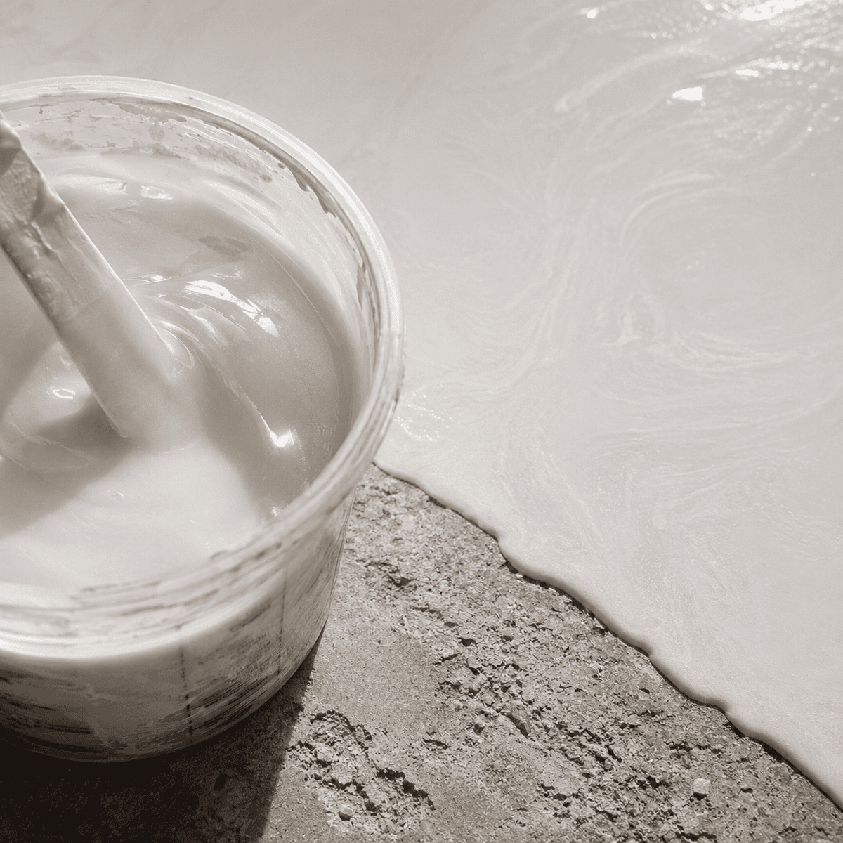 Cocaine-weißes Metallic-Epoxidharz im Mischbecher neben einer frisch beschichteten Betonfläche mit feinem Perleffekt, dezenter Marmorstruktur und elegantem Hochglanz-Finish.