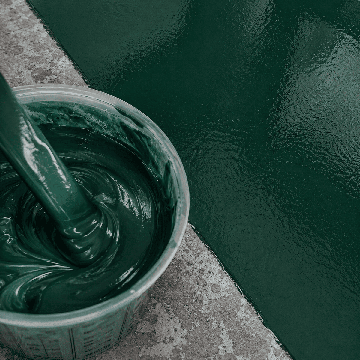 Deep Green UV Metallic-Epoxidharz im Mischbecher neben einer frisch beschichteten Betonfläche mit sattgrünem Farbton, feinem Perleffekt und glänzender Oberfläche.