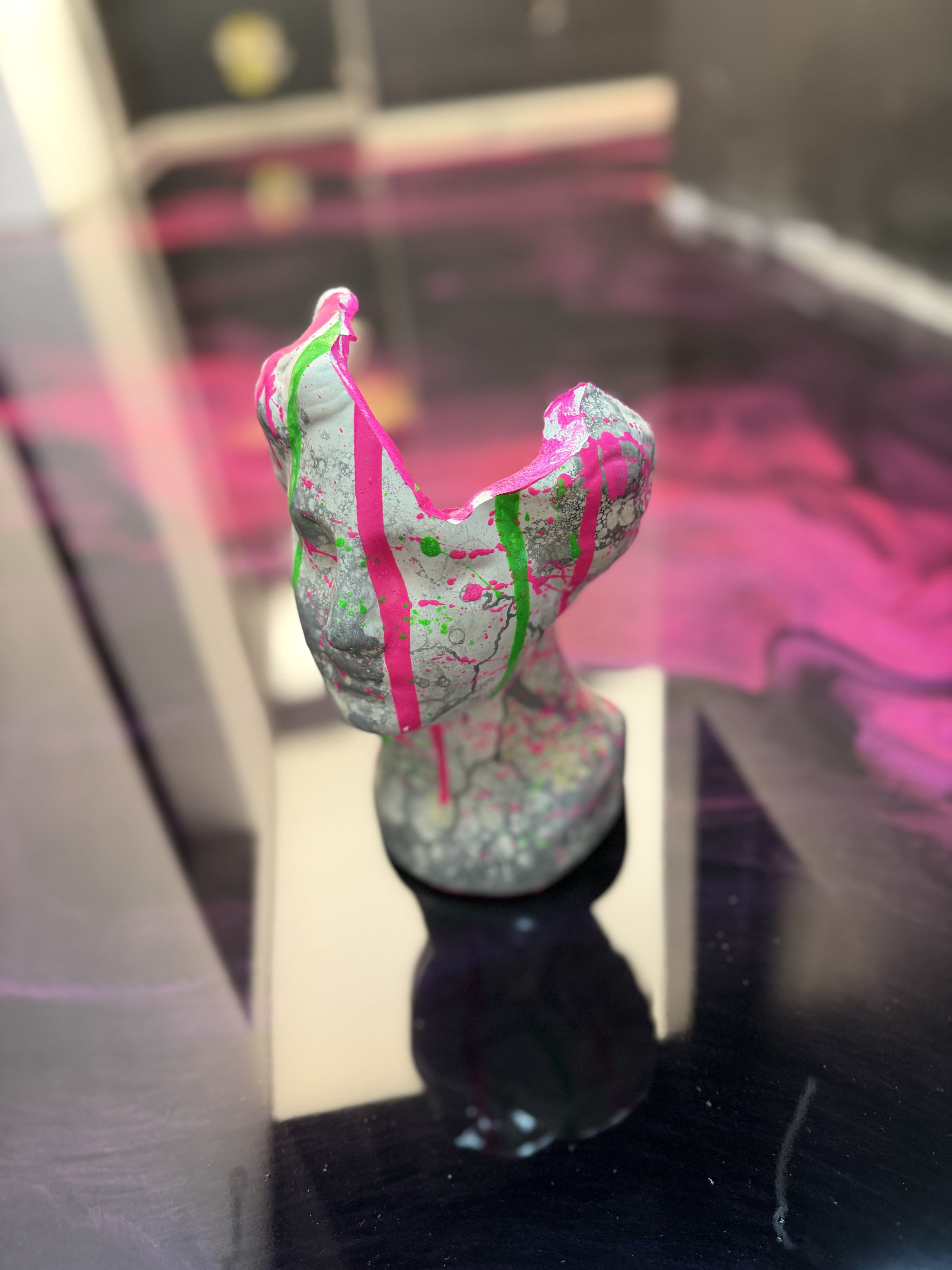 Handgefertigte Epoxidharz-Büstenfigur mit pinken und grünen Farbakzenten auf einem schwarzen Metallic-Epoxidharz-Boden als moderne Dekoration.