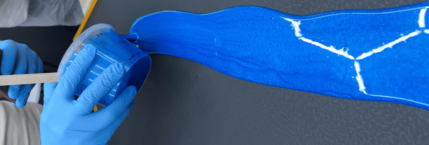 Blaues Epoxidharz in Cobalt Blue wird auf eine Oberfläche gegossen und erzeugt eine gleichmäßige, hochglänzende Beschichtung.