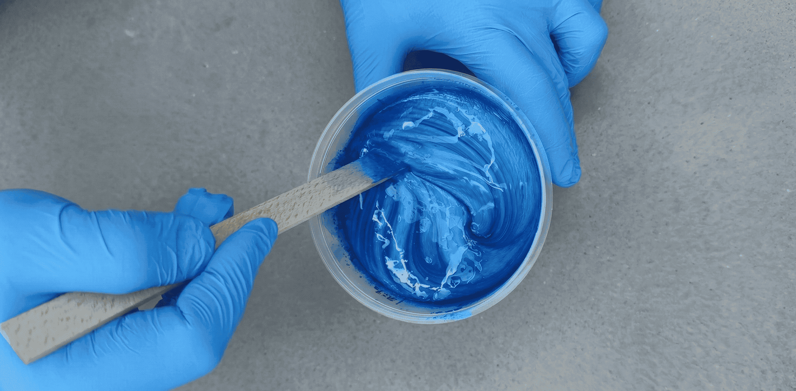 Blaues Epoxidharz in Cobalt Blue wird mit einem Holzspatel im Mischbecher gleichmäßig angerührt.