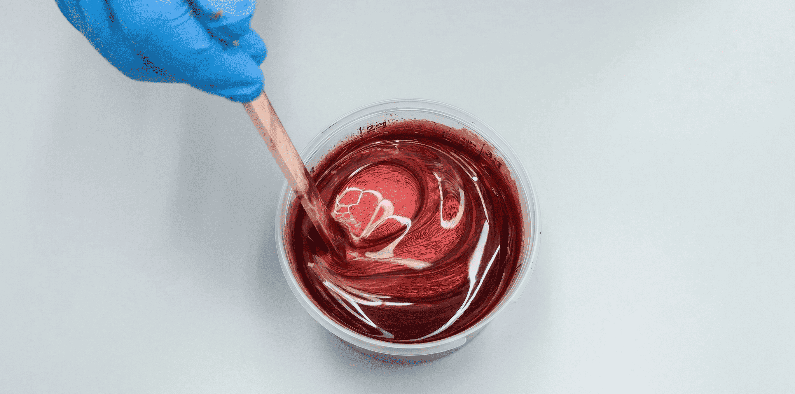 Rotes Metallic-Epoxidharz in Mauve wird mit einem Holzspatel im Mischbecher gleichmäßig angerührt.