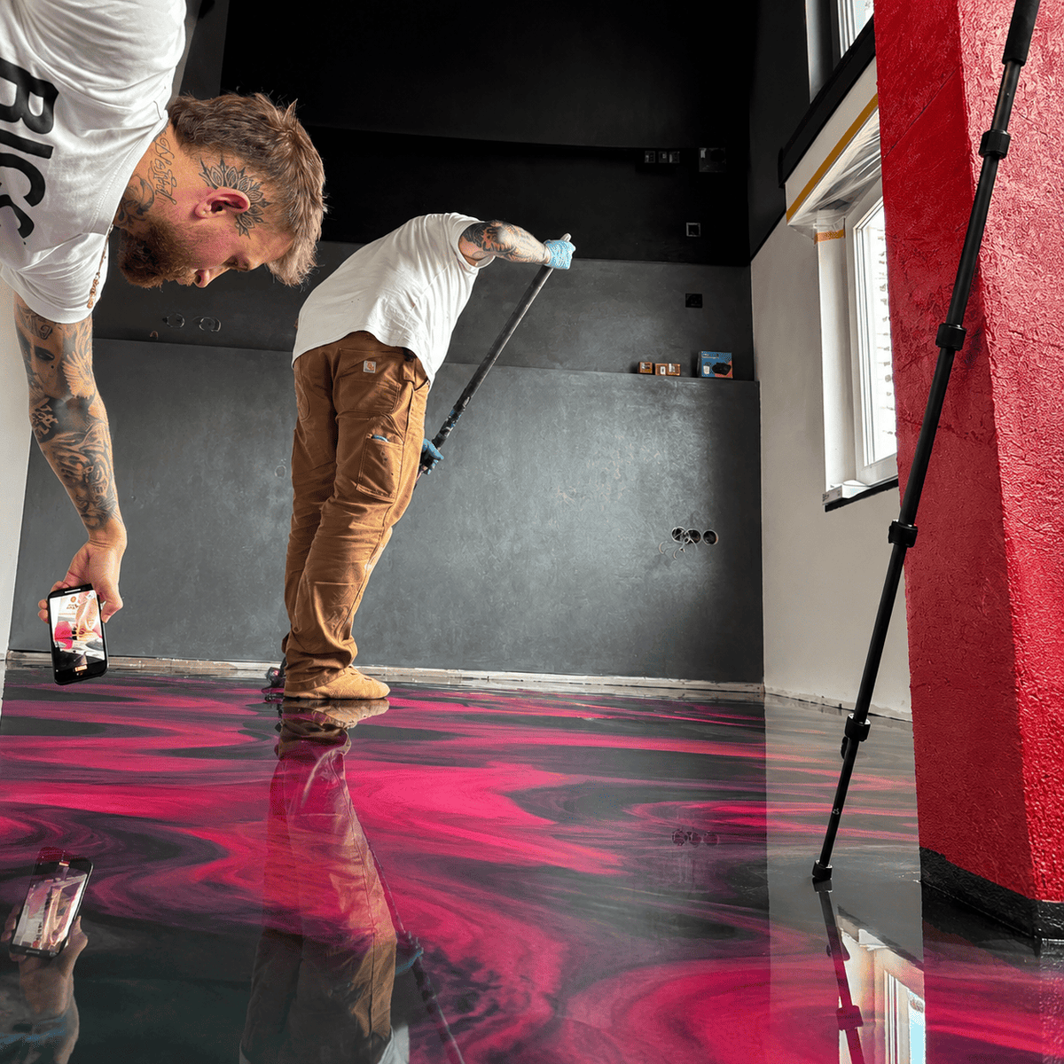 Reality Star Gigi filmt seinen schwarzen Metallic-Epoxidharz-Boden mit leuchtenden Magenta- und Violett-Effekten sowie fugenloser Hochglanzoberfläche im modernen Wohnbereich.