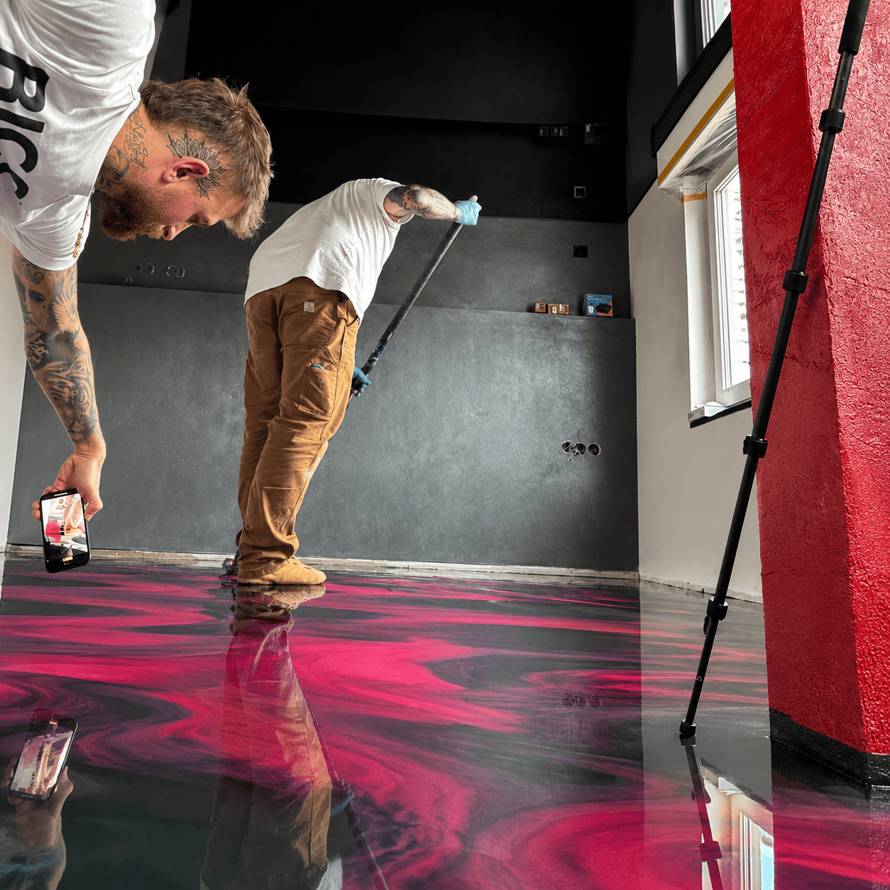 Reality Star Gigi filmt seinen schwarzen Metallic-Epoxidharz-Boden mit leuchtenden Magenta- und Violett-Effekten sowie fugenloser Hochglanzoberfläche im modernen Wohnbereich.