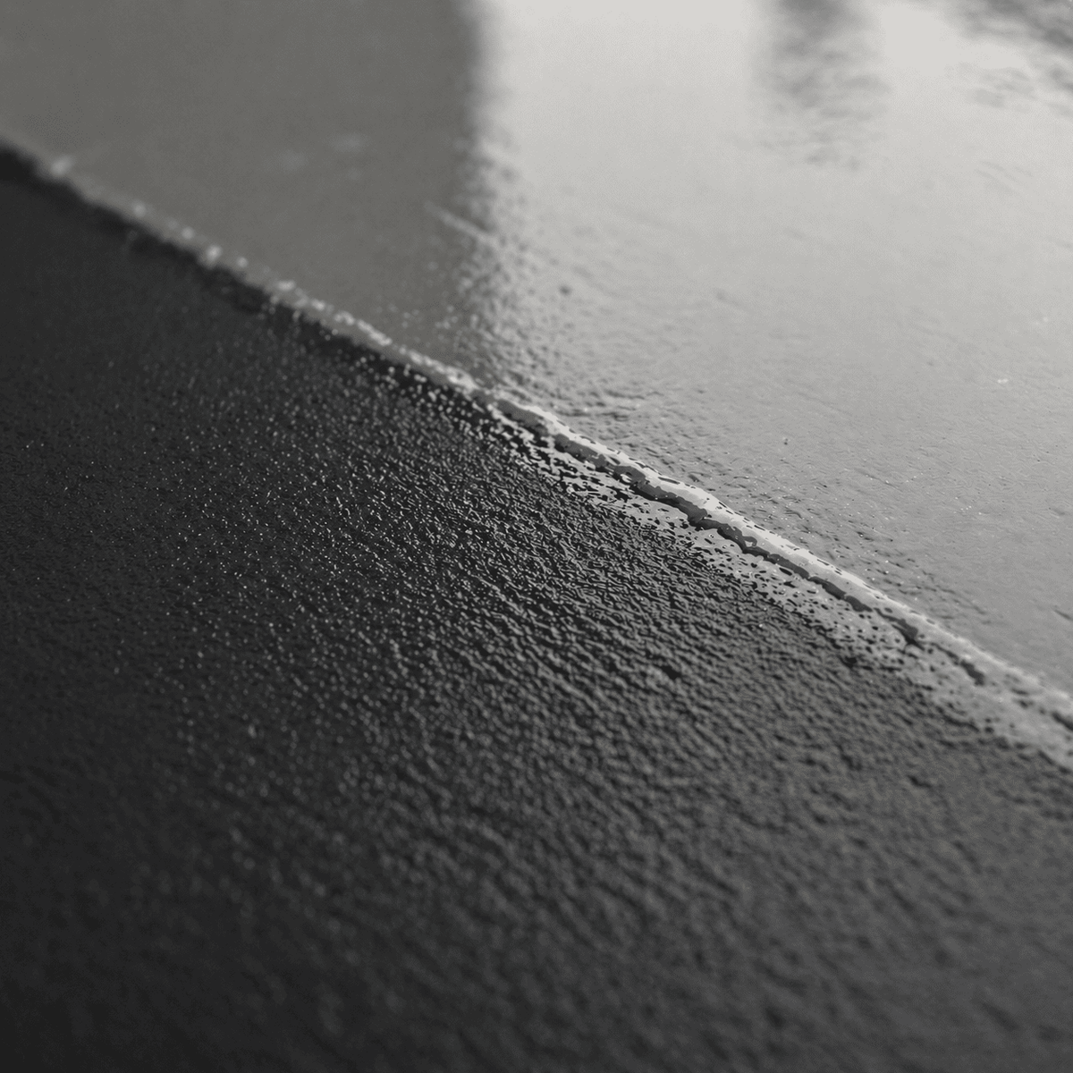 Nahaufnahme einer frisch aufgetragenen schwarzen Epoxidharz-Grundierung mit gleichmäßig verlaufender Schicht, feiner Oberflächenstruktur und optimaler Benetzung des Betonuntergrunds – die perfekte Basis für einen langlebigen Metallic-Epoxidharz-Boden.