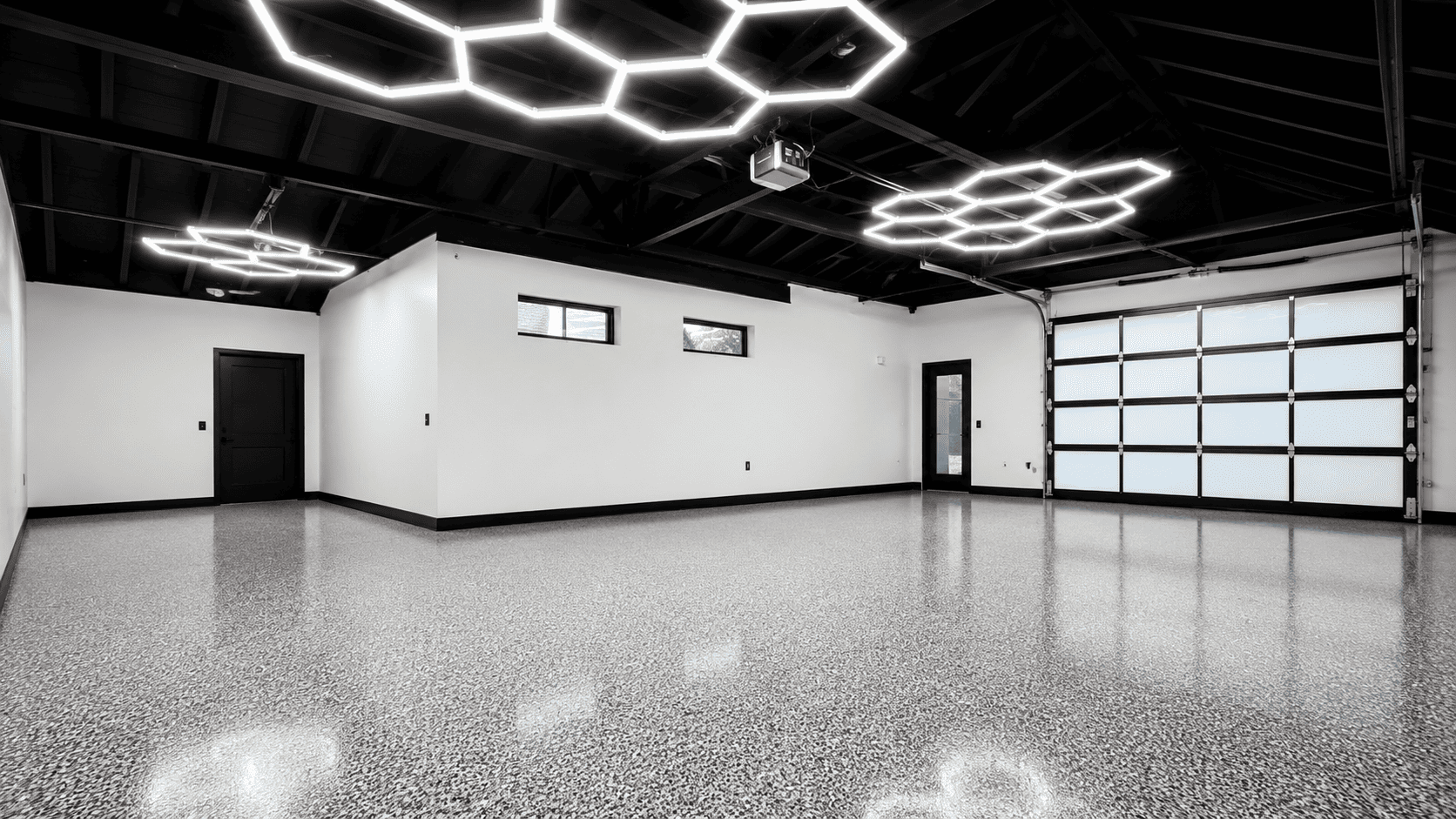 Große Garage mit grauem Epoxidharzboden in Chips-Optik, glänzender Oberfläche und moderner Hexagon-Beleuchtung