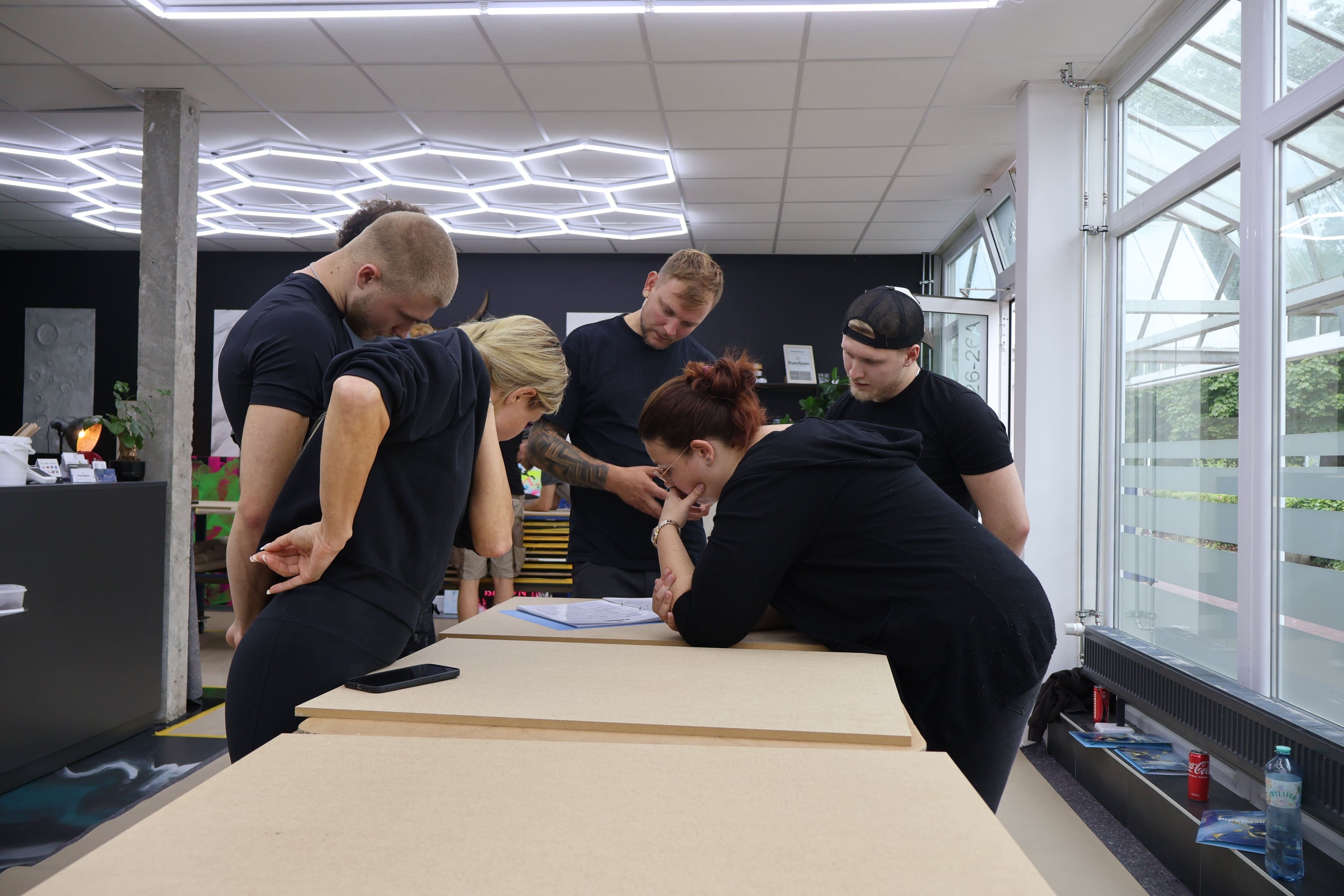 Teilnehmer eines Epoxidharz-Workshops besprechen gemeinsam Verarbeitungstechniken und Projektplanung während der theoretischen Schulung.