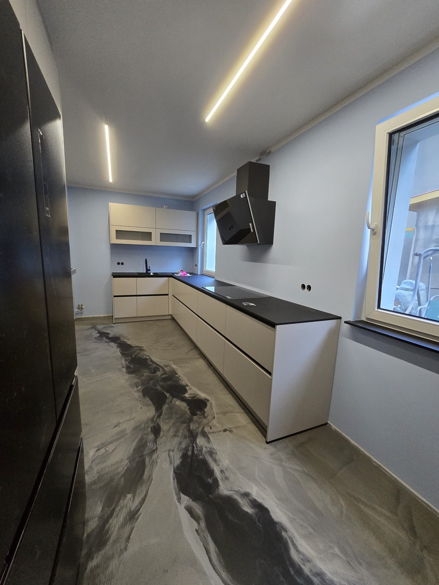 Grauer Metallic-Epoxidharz-Boden mit schwarzem Marmoreffekt in einer modernen Küche mit fugenloser Hochglanzoberfläche.