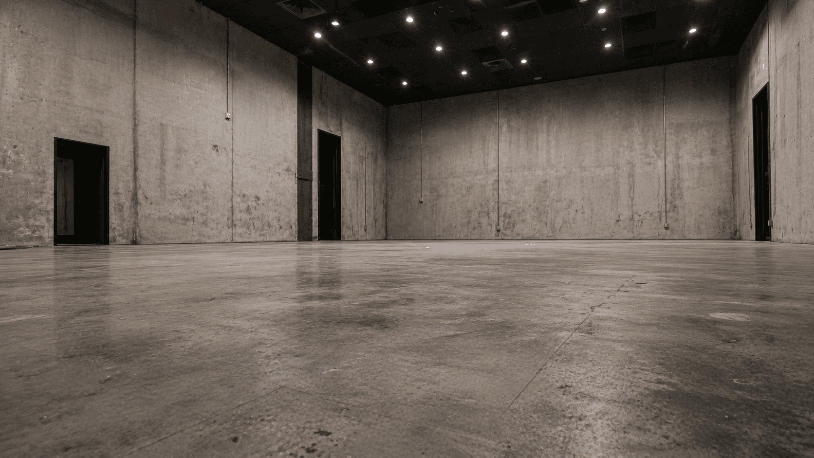 Leere Gewerbehalle mit unbehandeltem Betonboden und Sichtbetonwänden vor der Gestaltung mit Epoxidharz-Designboden
