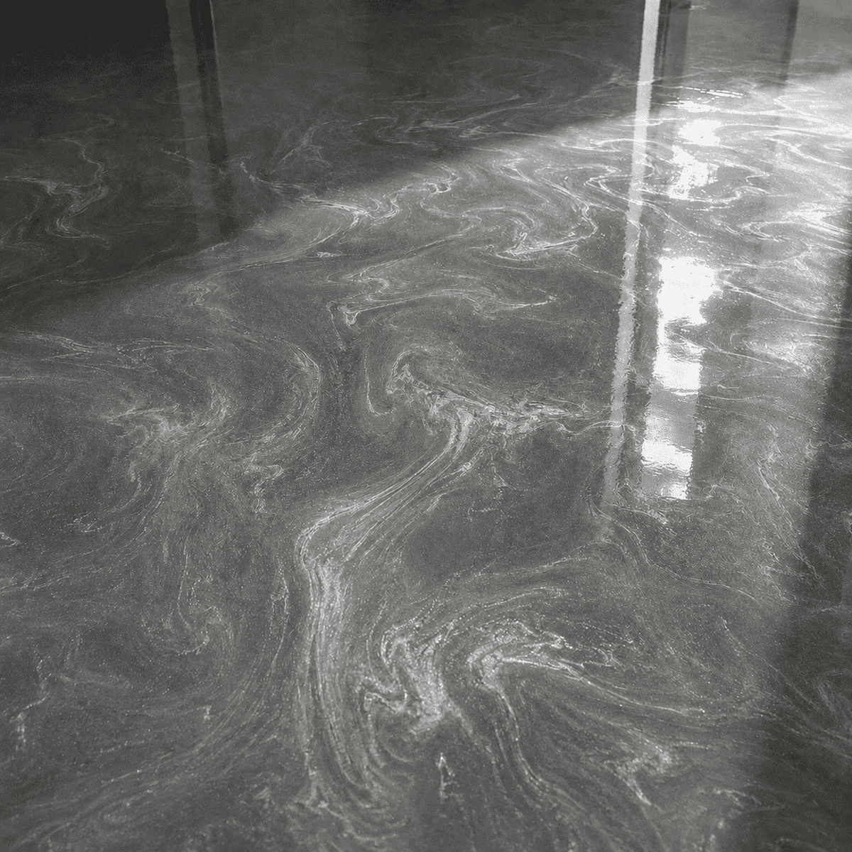 Silbergrauer Metallic-Epoxidharzboden mit feiner Marmorierung und brillanten Lichtreflexen bei direkter Sonneneinstrahlung.