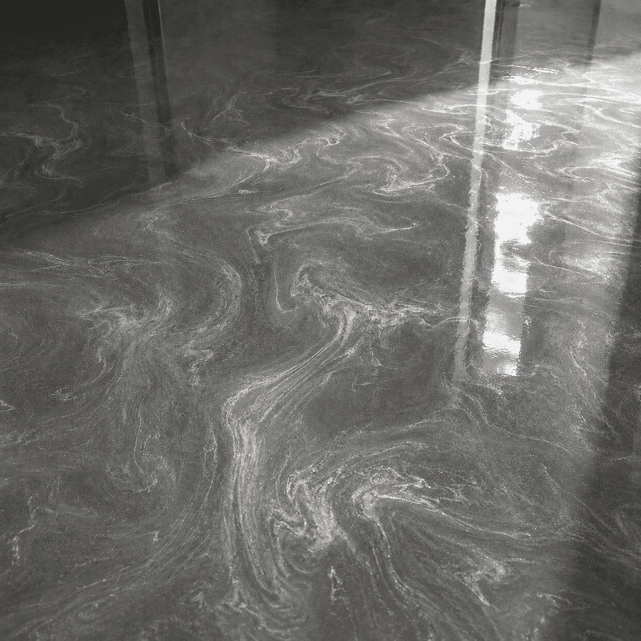 Silbergrauer Metallic-Epoxidharzboden mit feiner Marmorierung und brillanten Lichtreflexen bei direkter Sonneneinstrahlung.