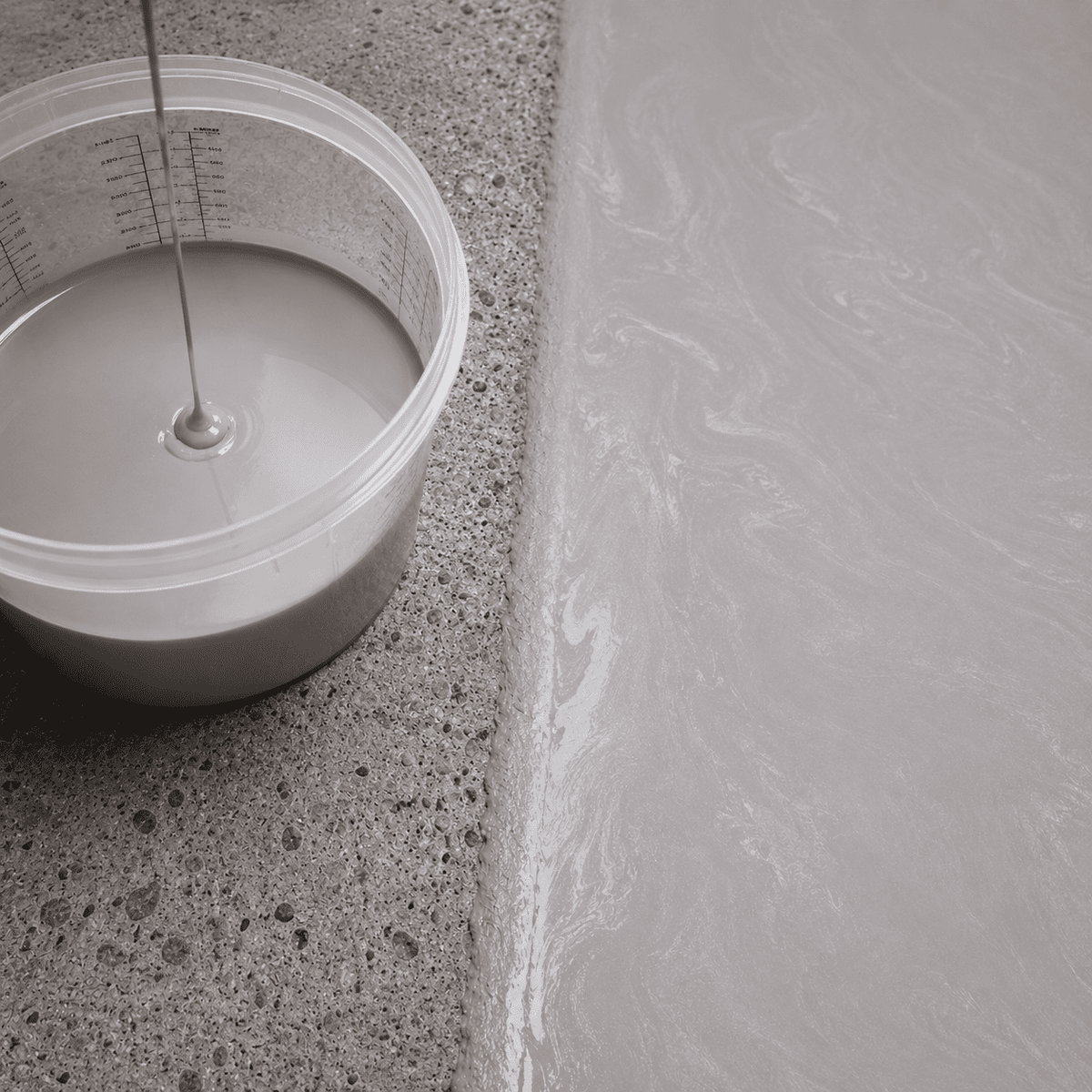Hellsilbernes Metallic-Epoxidharz im Mischbecher neben einer frisch beschichteten Betonfläche mit feinem Perlglanz, dezenter Marmorstruktur und elegantem Hochglanz-Finish.