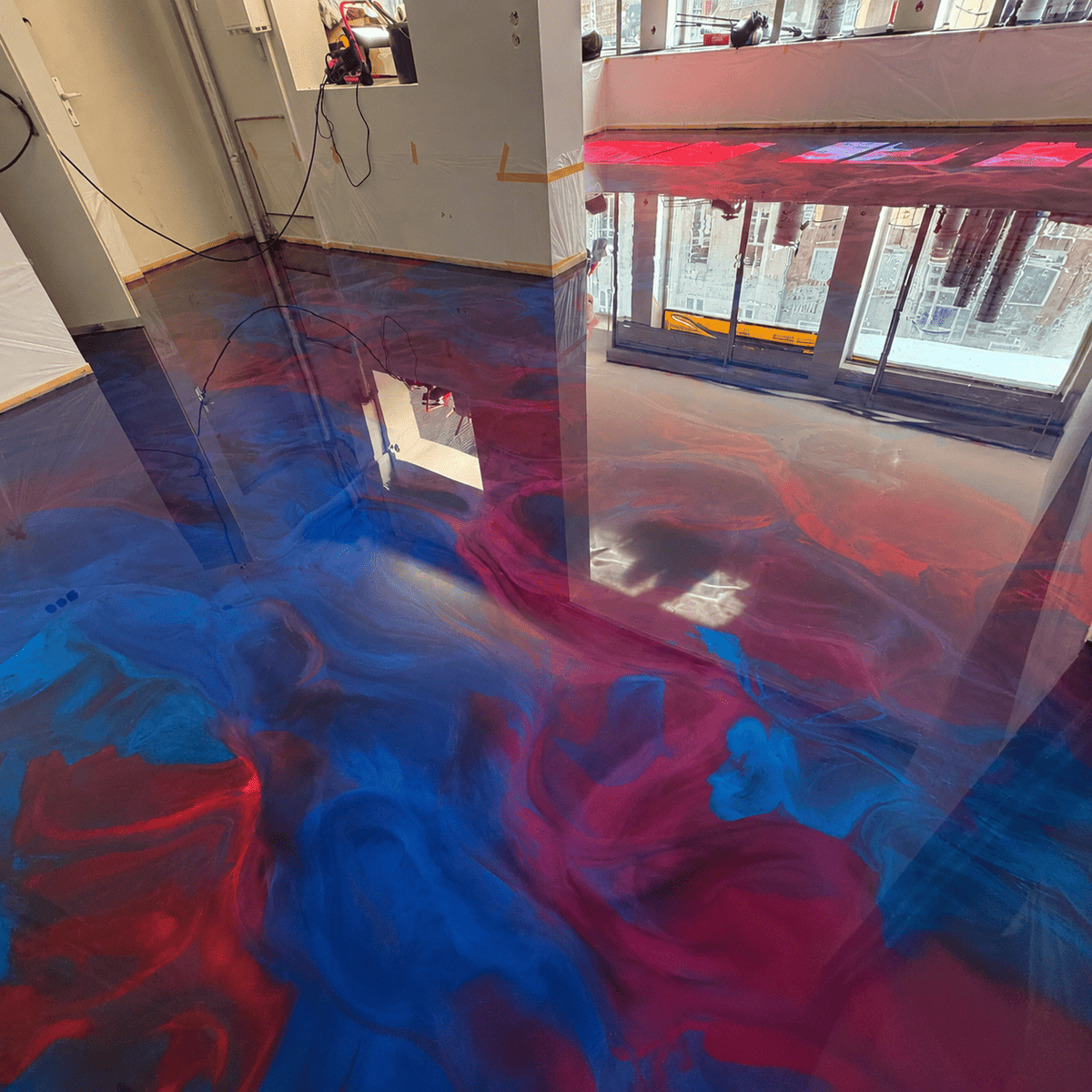 Glänzender Metallic-Epoxidharzboden in Blau und Rot mit Marmoreffekt in einem modern renovierten Innenraum.
