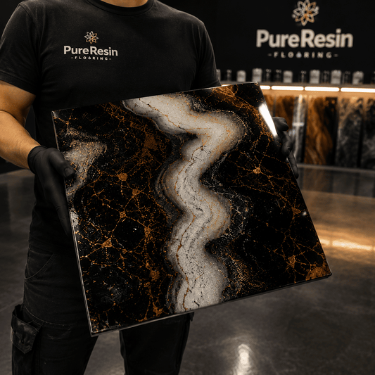 Ein Mann in schwarzen Tshirt hält eine Musterplatte in Marmor Look in Schwarz, Weiß, Gold in der Hand