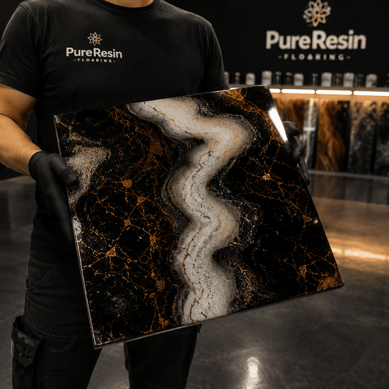 Ein Mann in schwarzen Tshirt hält eine Musterplatte in Marmor Look in Schwarz, Weiß, Gold in der Hand