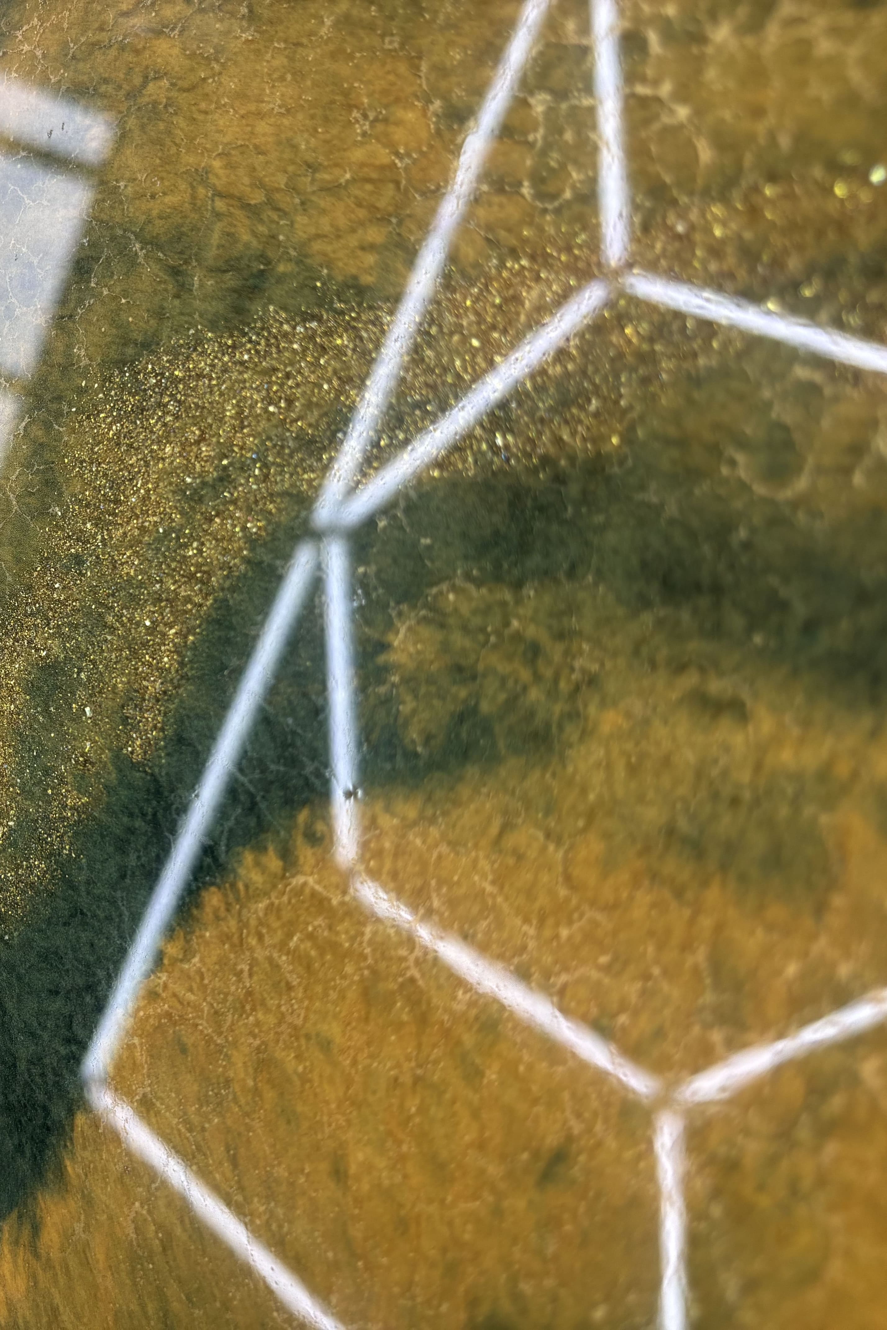 Detailaufnahme einer Metallic-Epoxidharz-Musterplatte in Gold- und Olivtönen mit schimmernden Pigmenten und geometrischem Design.