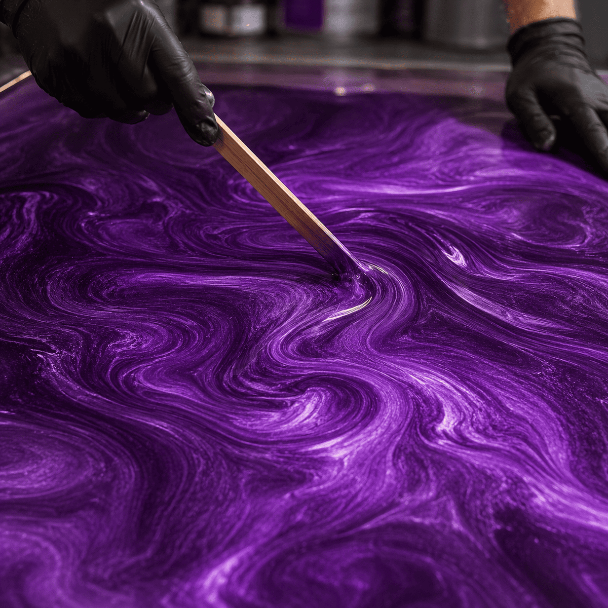 Royal Plum UV Metallic-Epoxidharz wird mit einem Holzspatel zu einer luxuriösen Marmorstruktur mit brillantem Perleffekt, intensivem Pflaumenviolett-Schimmer und faszinierender Tiefenwirkung gestaltet.