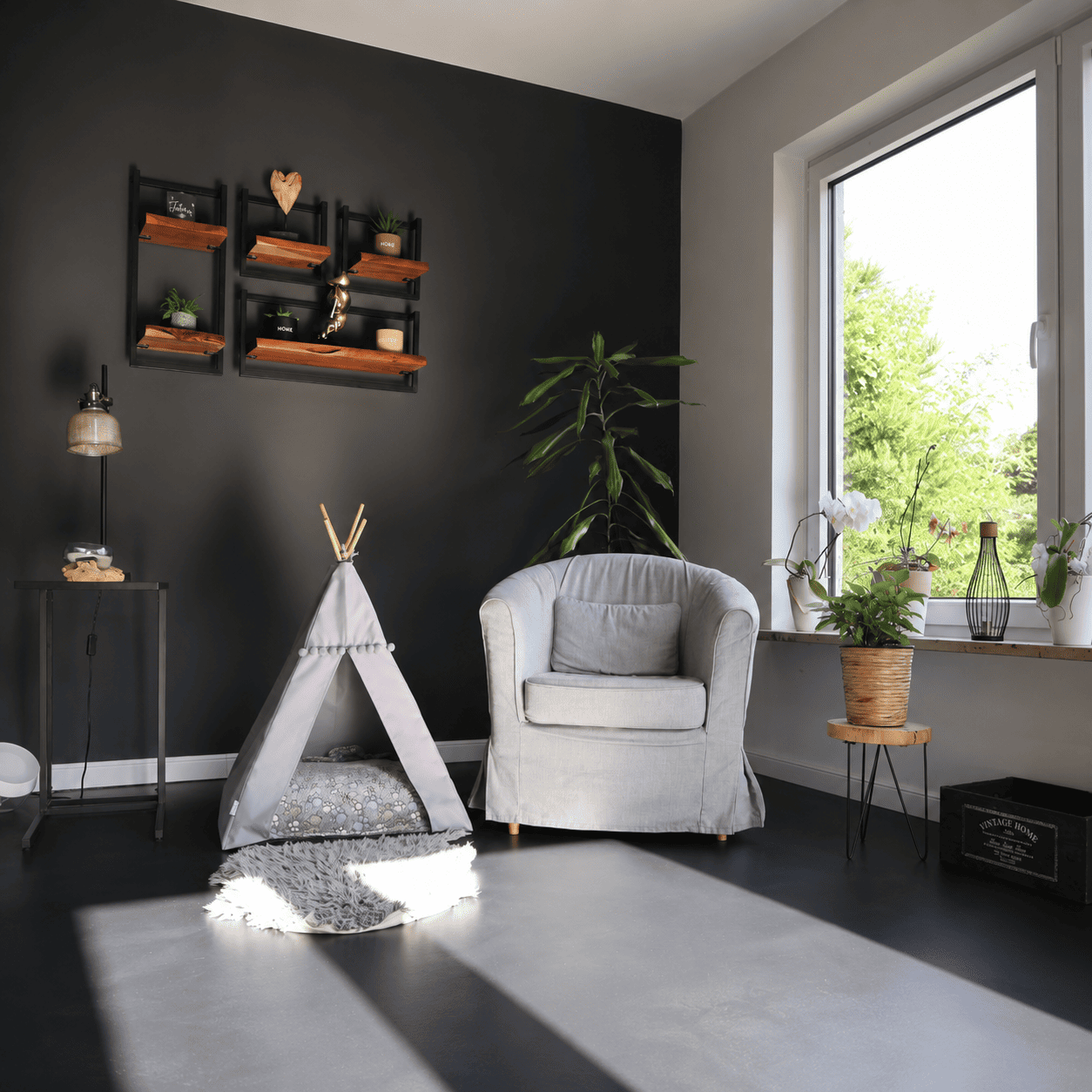 Modernes Wohnzimmer mit fugenlosem Designboden in elegantem Anthrazit. Die matte Epoxidharz-Beschichtung verleiht dem Raum eine zeitlose, minimalistische Optik und harmoniert perfekt mit der dunklen Akzentwand, hellen Möbeln und natürlichen Holzelementen.