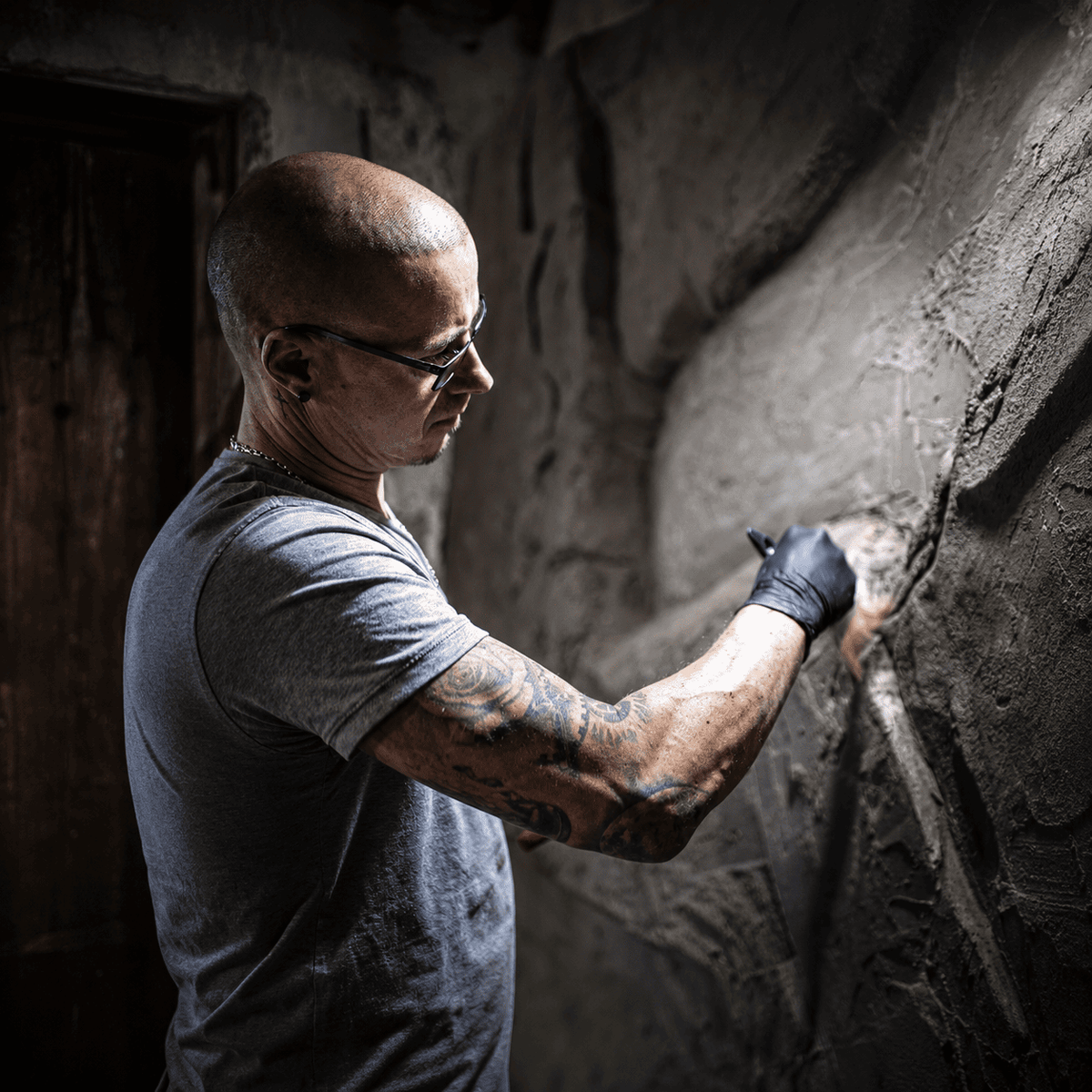 Handwerker modelliert und verfeinert eine künstliche Felswand für eine realistische Natursteinoptik.