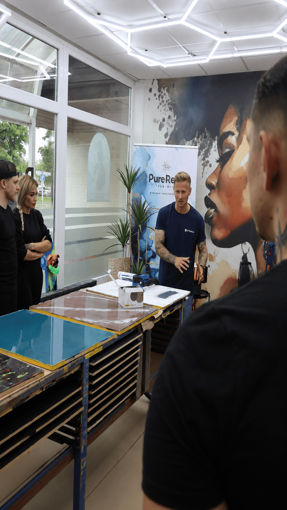 Trainer erklärt Teilnehmern im Pure Resin Flooring Workshop professionelle Techniken zur Verarbeitung von Epoxidharz-Bodenbeschichtungen.