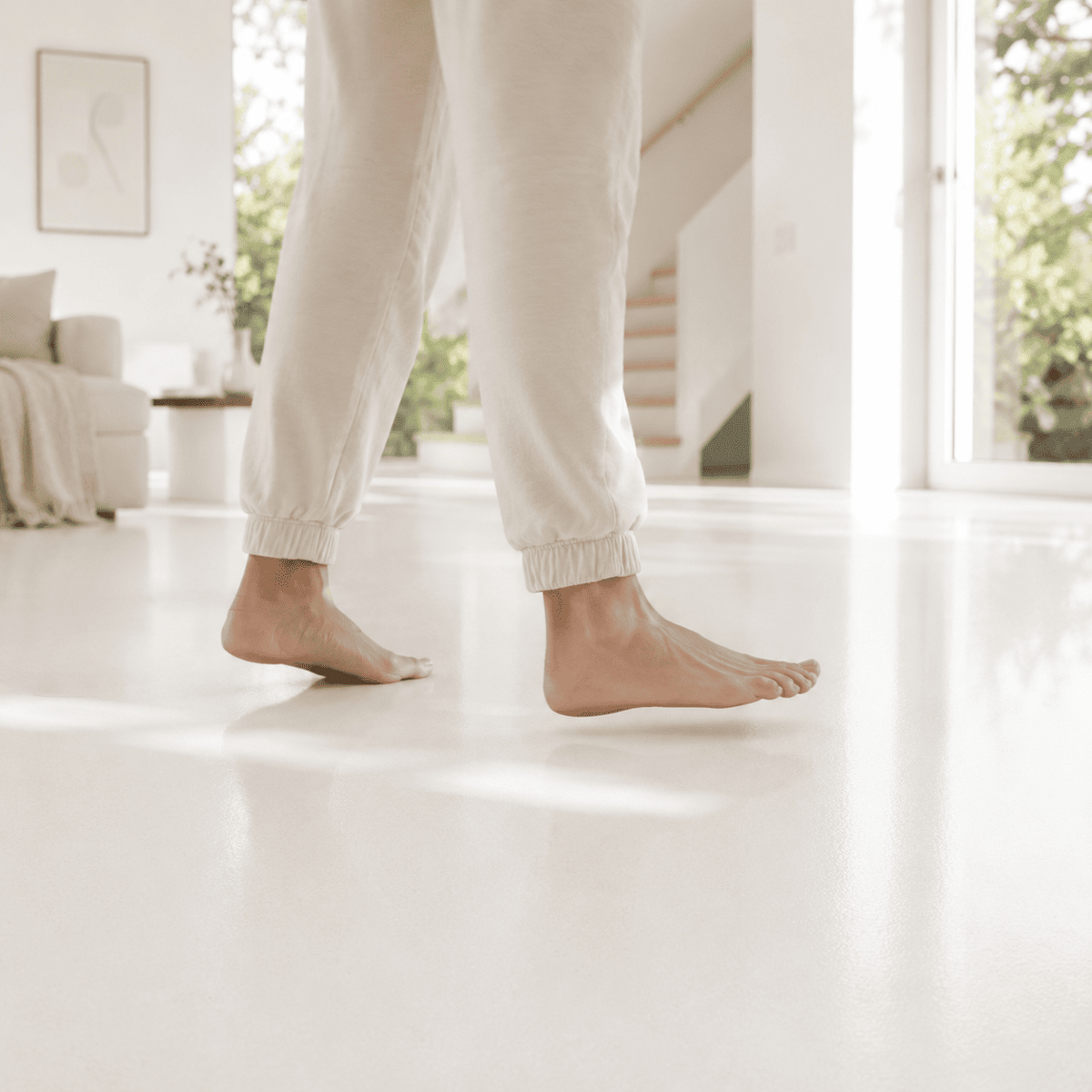 Serin Pure White Designboden mit fugenloser, weißer Oberfläche in hellem Wohnraum, barfuß begangen für angenehmen Gehkomfort.