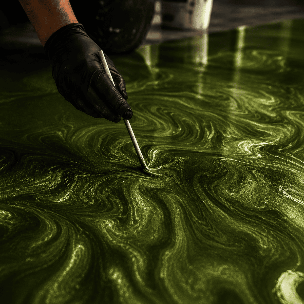 Schwarz behandschuhte Hand gestaltet Strukturen in smaragdgrünem Metallic-Epoxidharz mit glänzender Tiefenwirkung.
