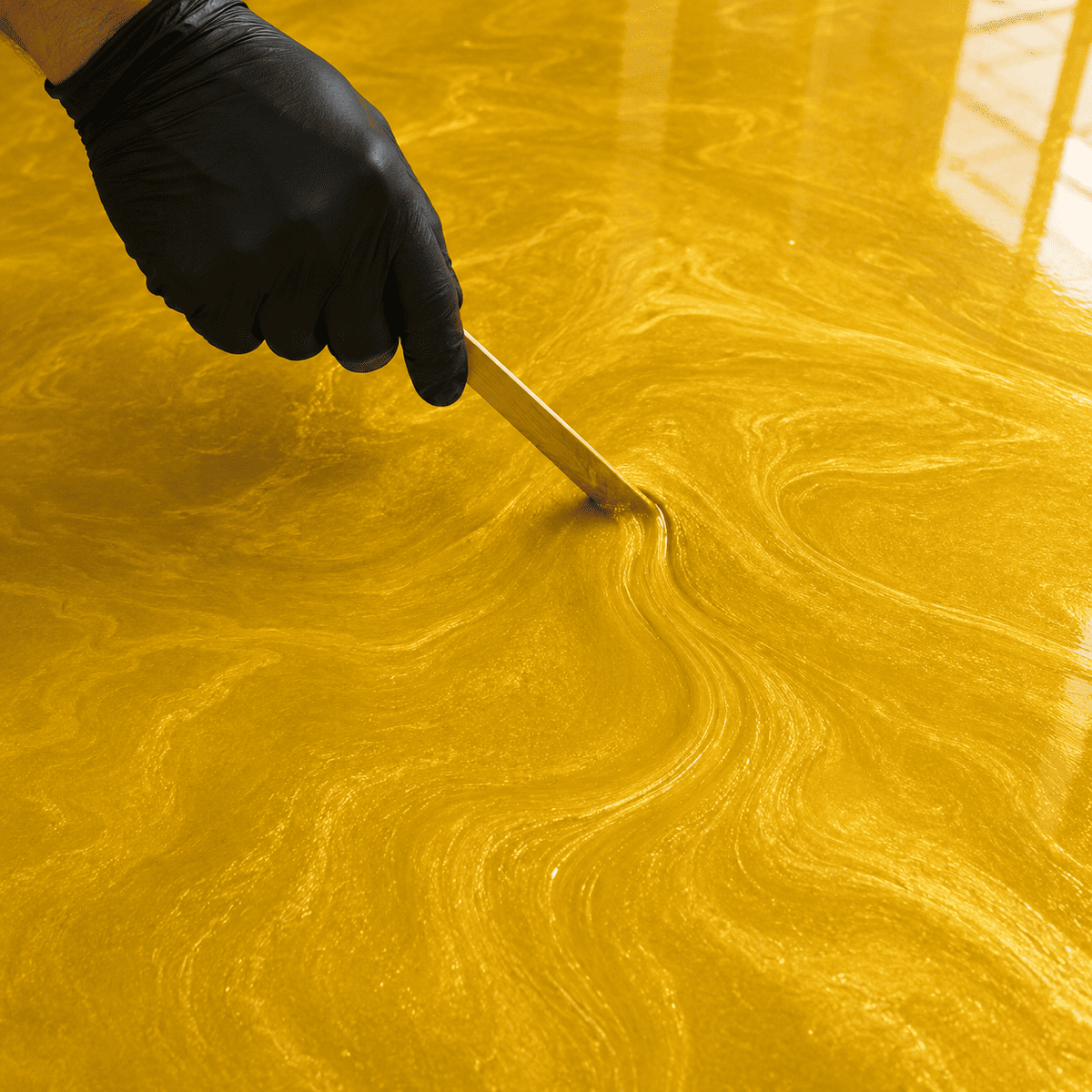 Sonnengelbes Metallic-Epoxidharz wird mit Holzstab zur Marmorstruktur gestaltet