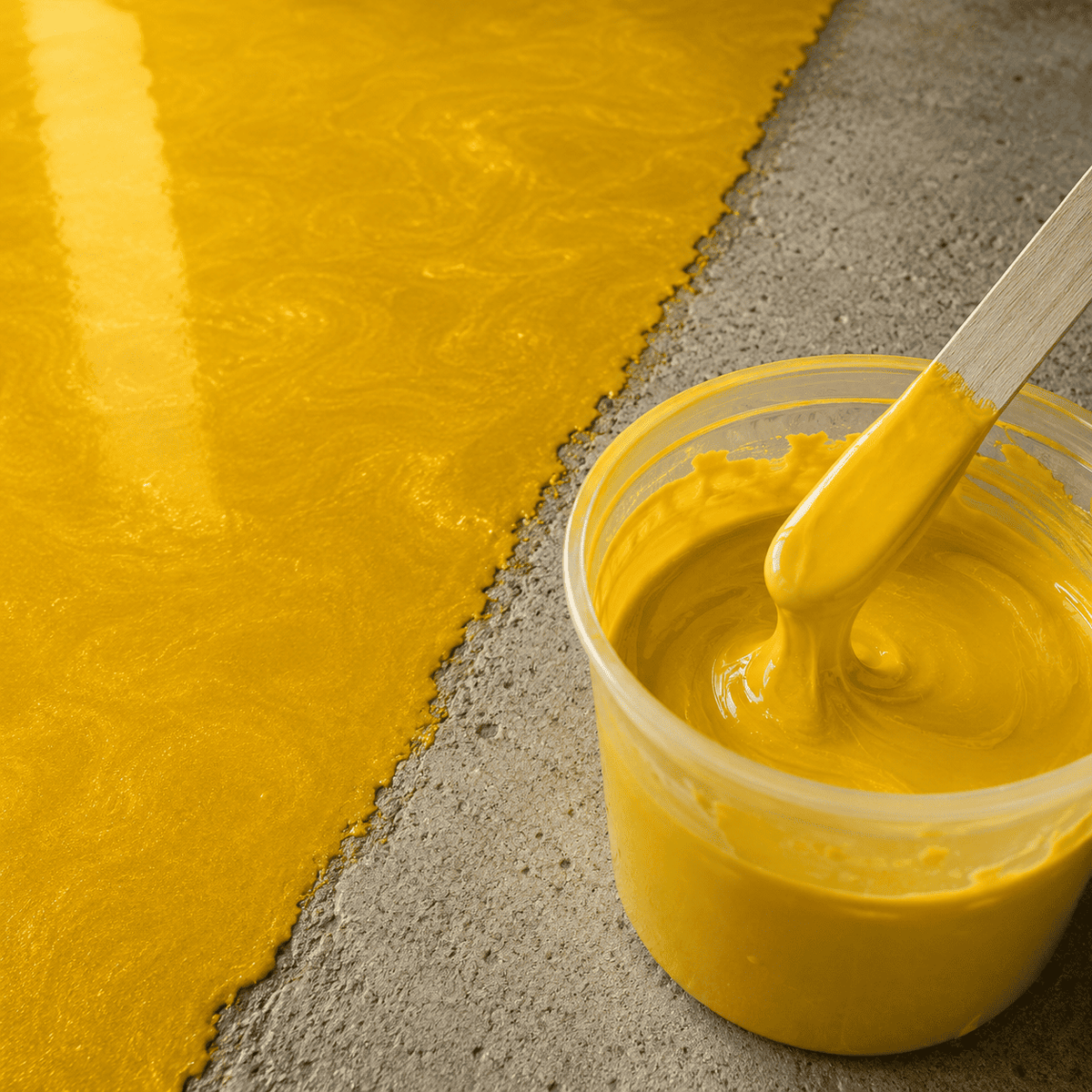 Sonnengelbes Metallic-Epoxidharz im Mischbecher und auf Betonboden aufgetragen