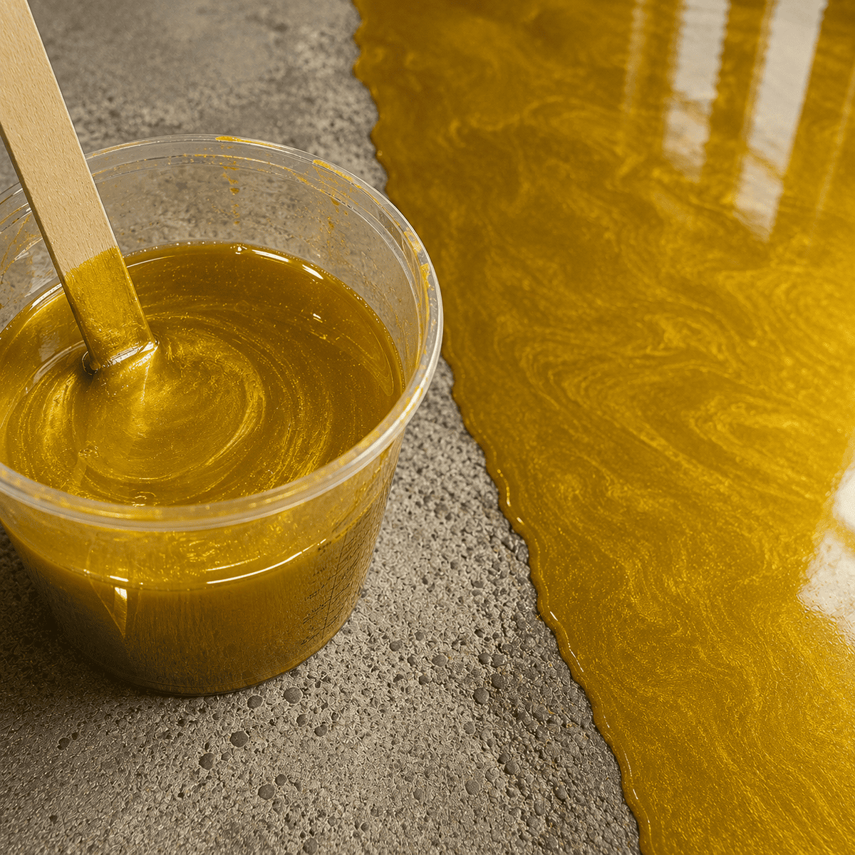 Sunset Gold UV Metallic-Epoxidharz im Mischbecher neben einer frisch beschichteten Betonfläche mit warmem Goldton, edlem Perleffekt, seidigem Schimmer und hochglänzender Tiefenwirkung.