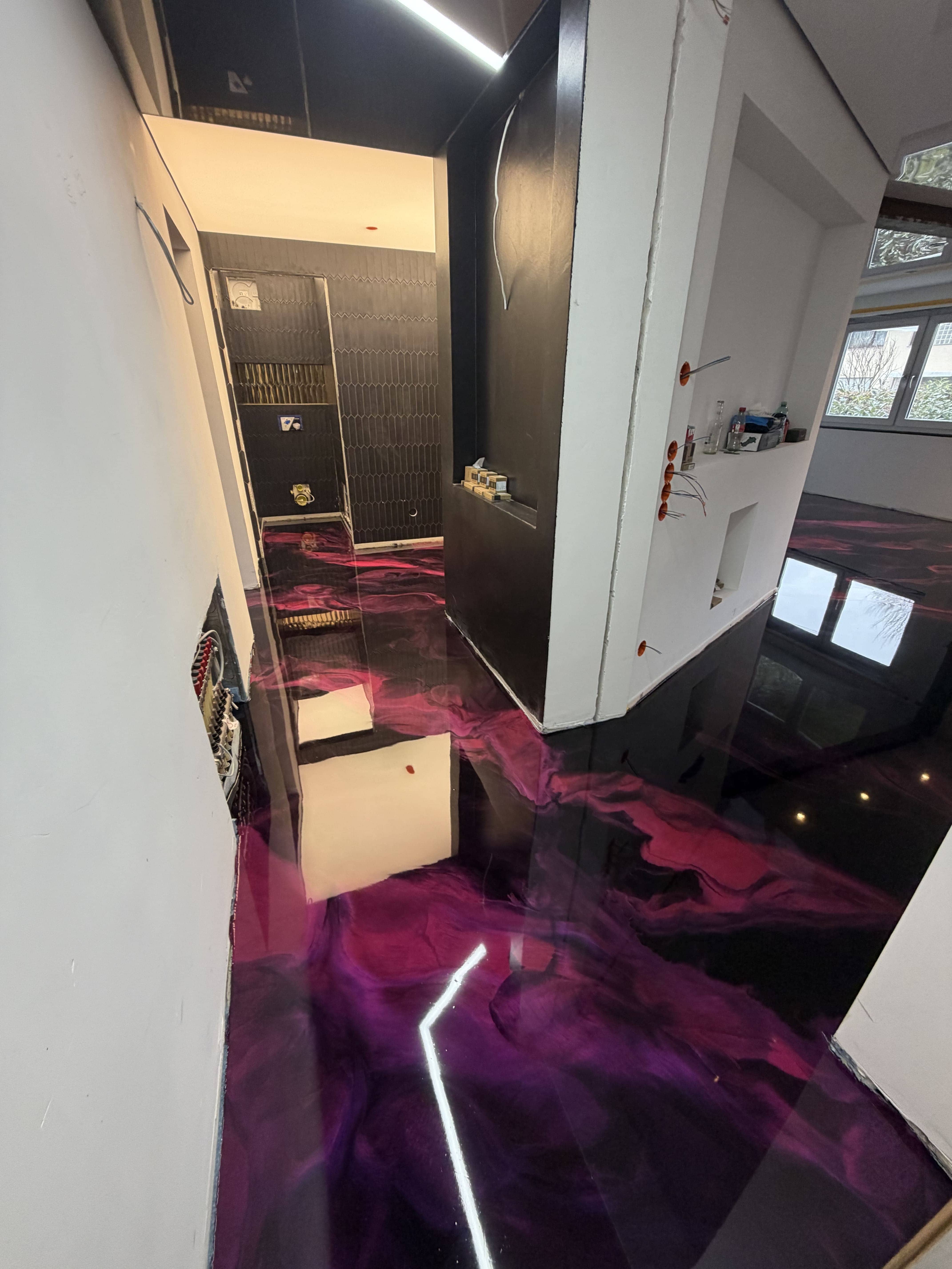 Fugenloser Metallic-Epoxidharz-Boden in Schwarz und Magenta mit Hochglanzoberfläche im modernen Wohnbereich und Badezimmer.