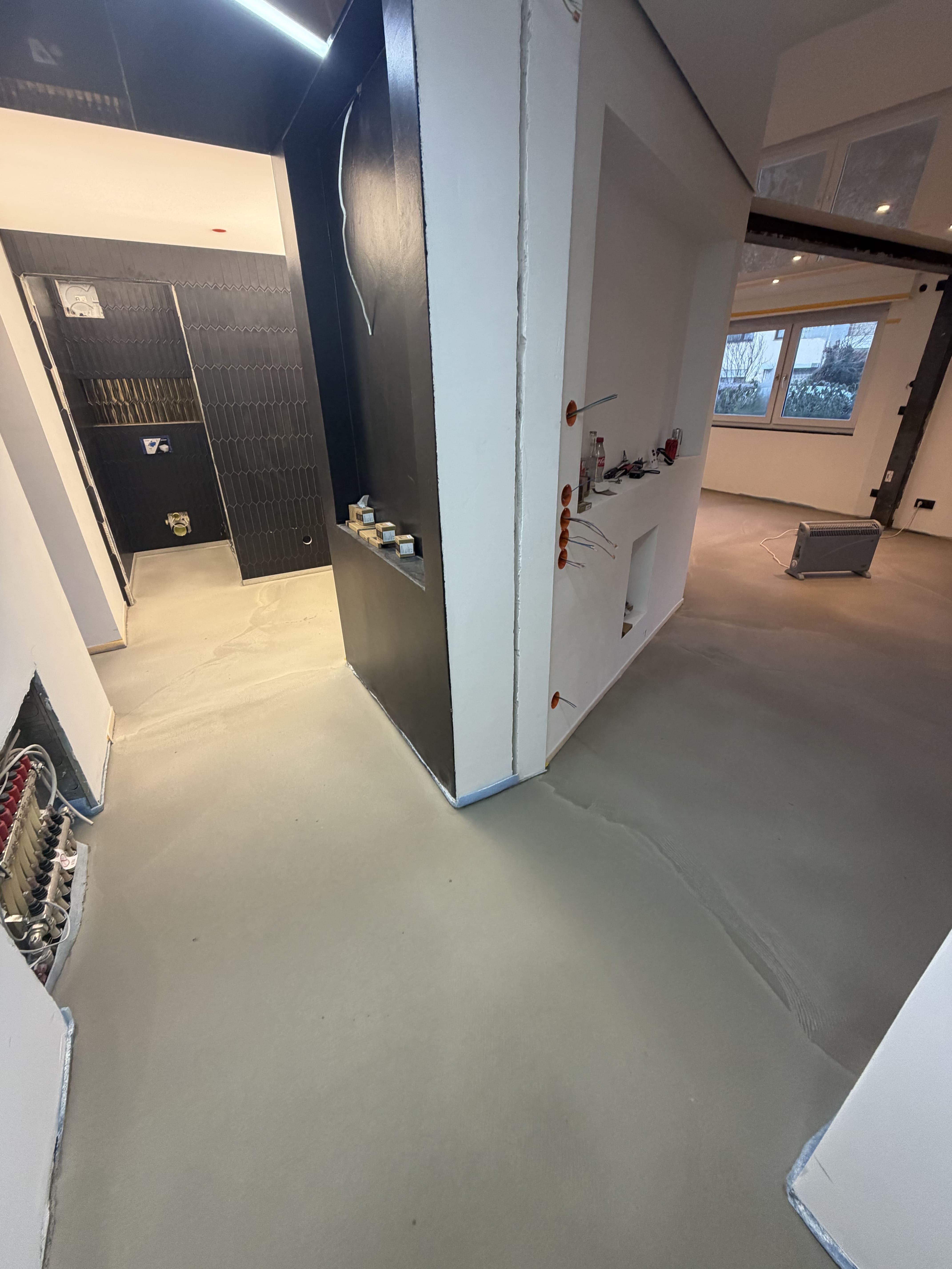 Grauer Beton Fussboden in Wohnbereich und Badezimmer vor dem dekorativen Bodenaufbau.