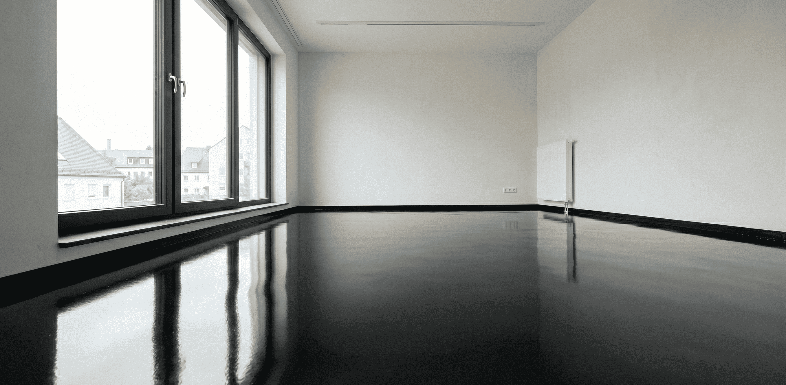 Schwarze Epoxidharz-Grundierung mit glänzender Oberfläche als Vorbereitung für einen dekorativen Metallic-Epoxidharz-Boden im Wohnbereich.